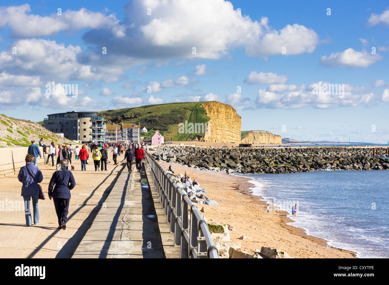 La gente caminando a lo largo de West Bay, Dorset, paseo marítimo en la costa de Dorset, Reino Unido Foto de stock