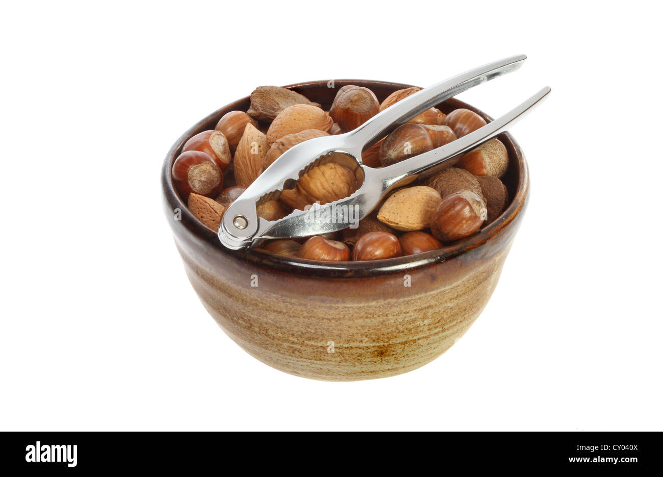 Las nueces enteras en un recipiente con un cracker aislado contra un blanco Foto de stock