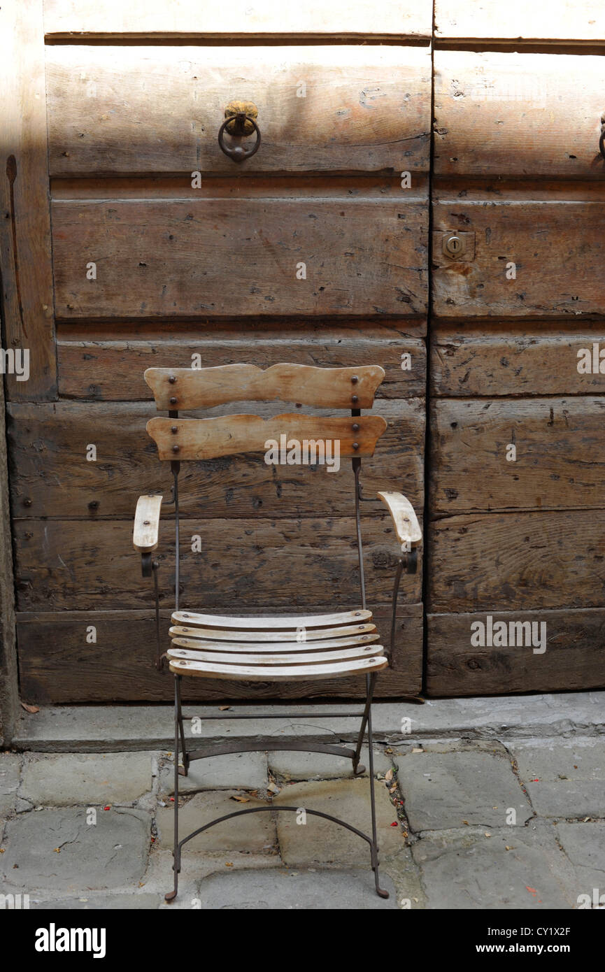 Metal y madera rústica silla enfrente de una antigua puerta en Montecatini Alto Toscana Italia Foto de stock