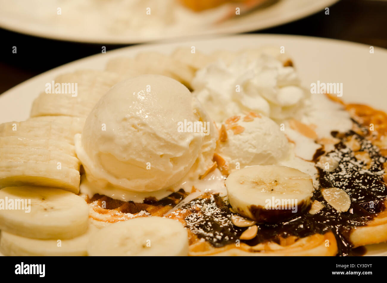 Barquillo de helado de vainilla con plátanos y nata montada Foto de stock