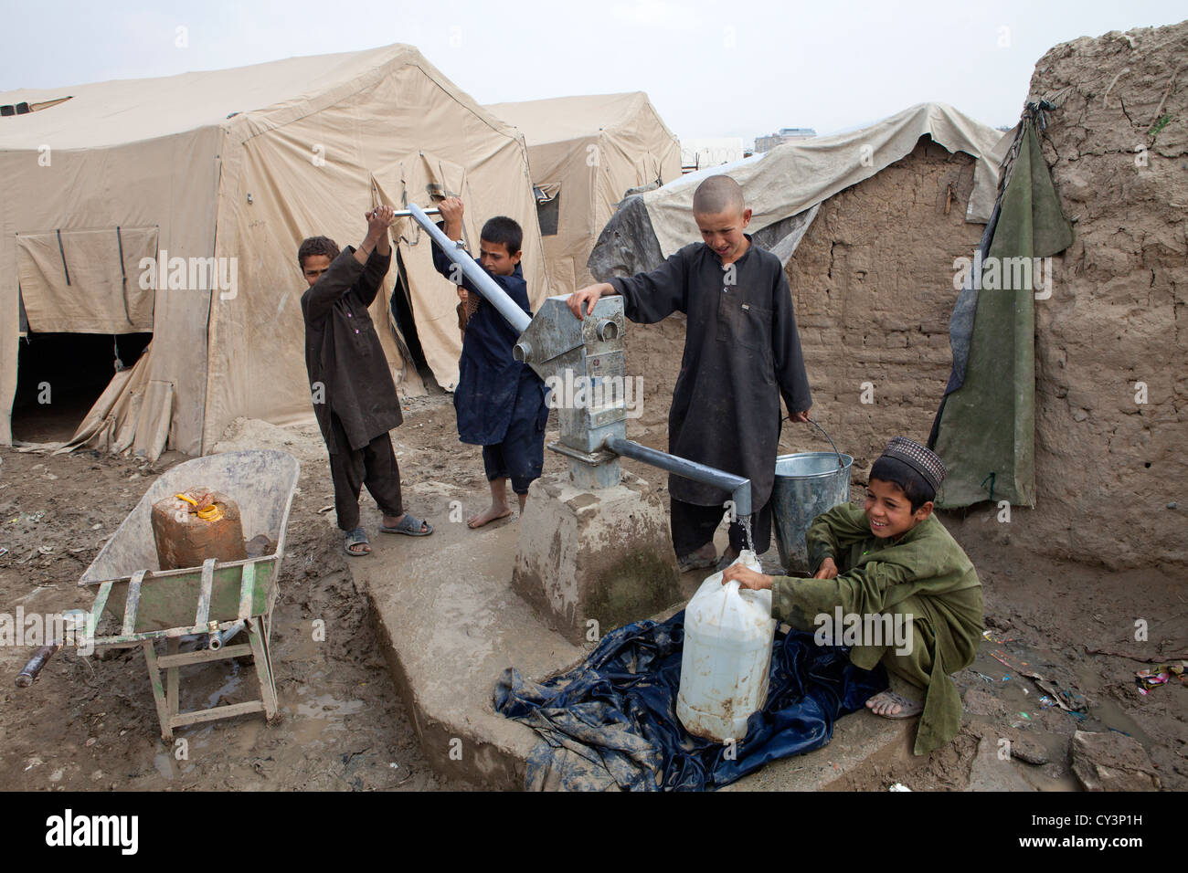 Niños refugiados afganos a acarrear agua del pozo Foto de stock