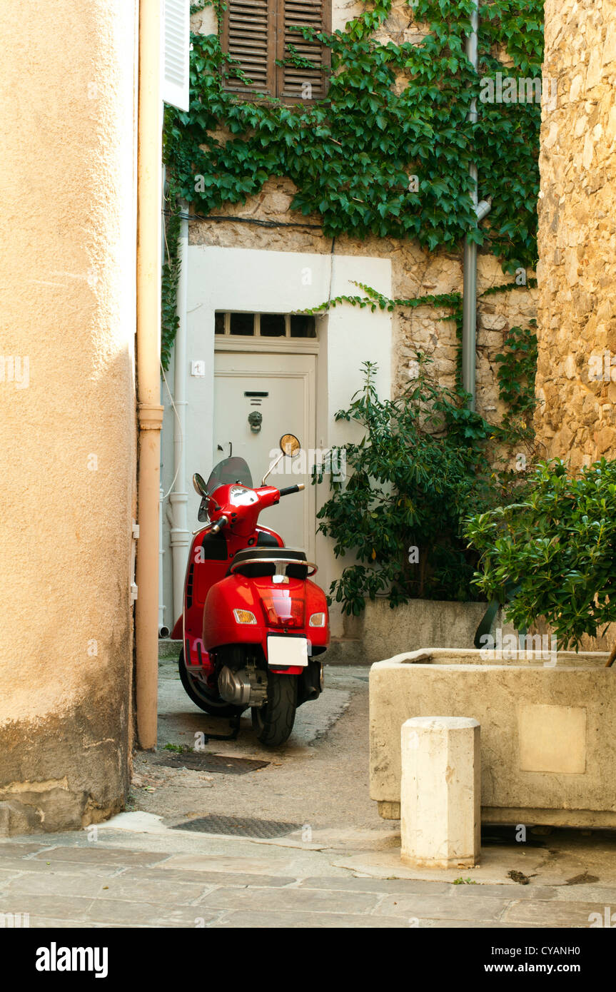 Pequeño scooter roja estacionada en el barrio antiguo de los edificios. Saint Tropez buildigs. Foto de stock