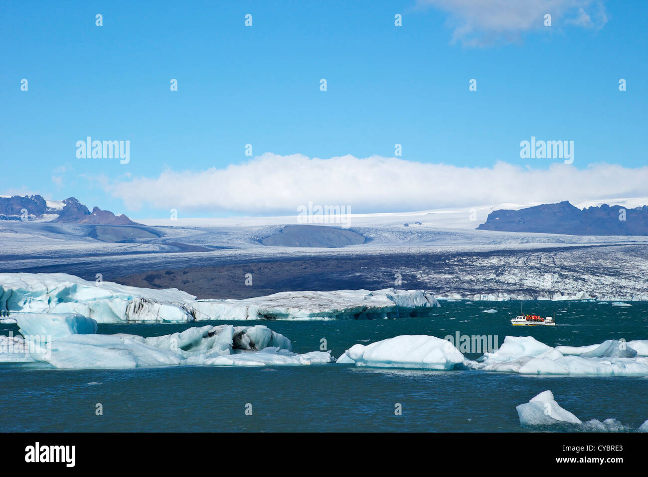 Barco anfibio para llevar a los turistas en el lago glaciar de Jokulsarlon con nieve en el casquete de hielo masiva de Vatnajokull detrás de Islandia Foto de stock