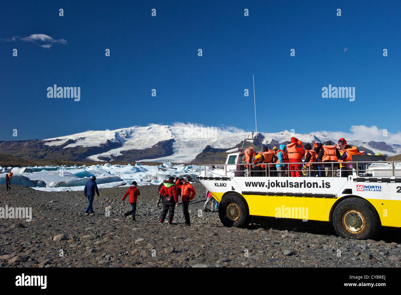 Barco anfibio para llevar a los turistas en el lago glaciar de Jokulsarlon con nieve en el casquete de hielo masiva de Vatnajokull detrás de Islandia Foto de stock