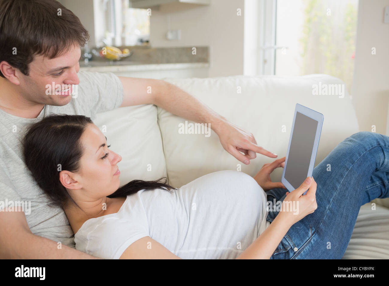Los futuros padres relajantes con tablet pc Foto de stock