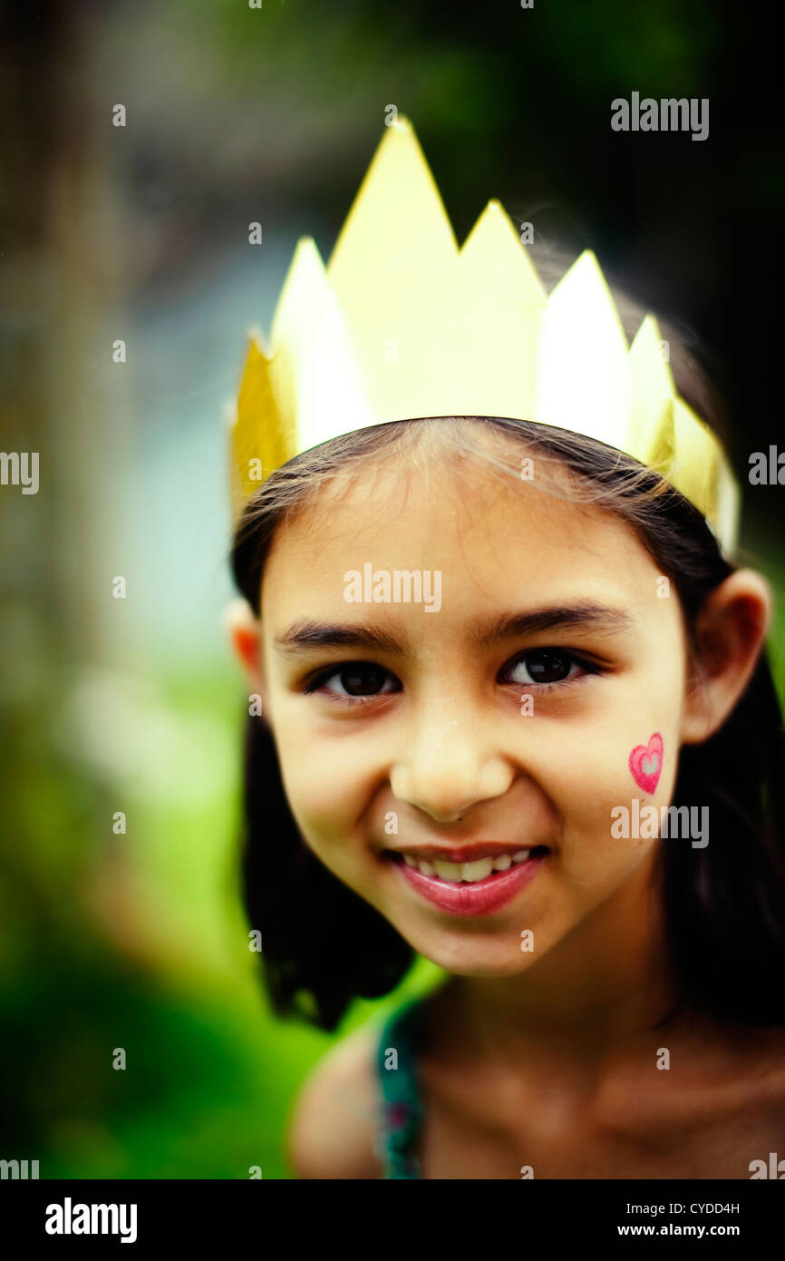 Chica con el corazón en la mejilla lleva su corona de princesa caseros Foto de stock
