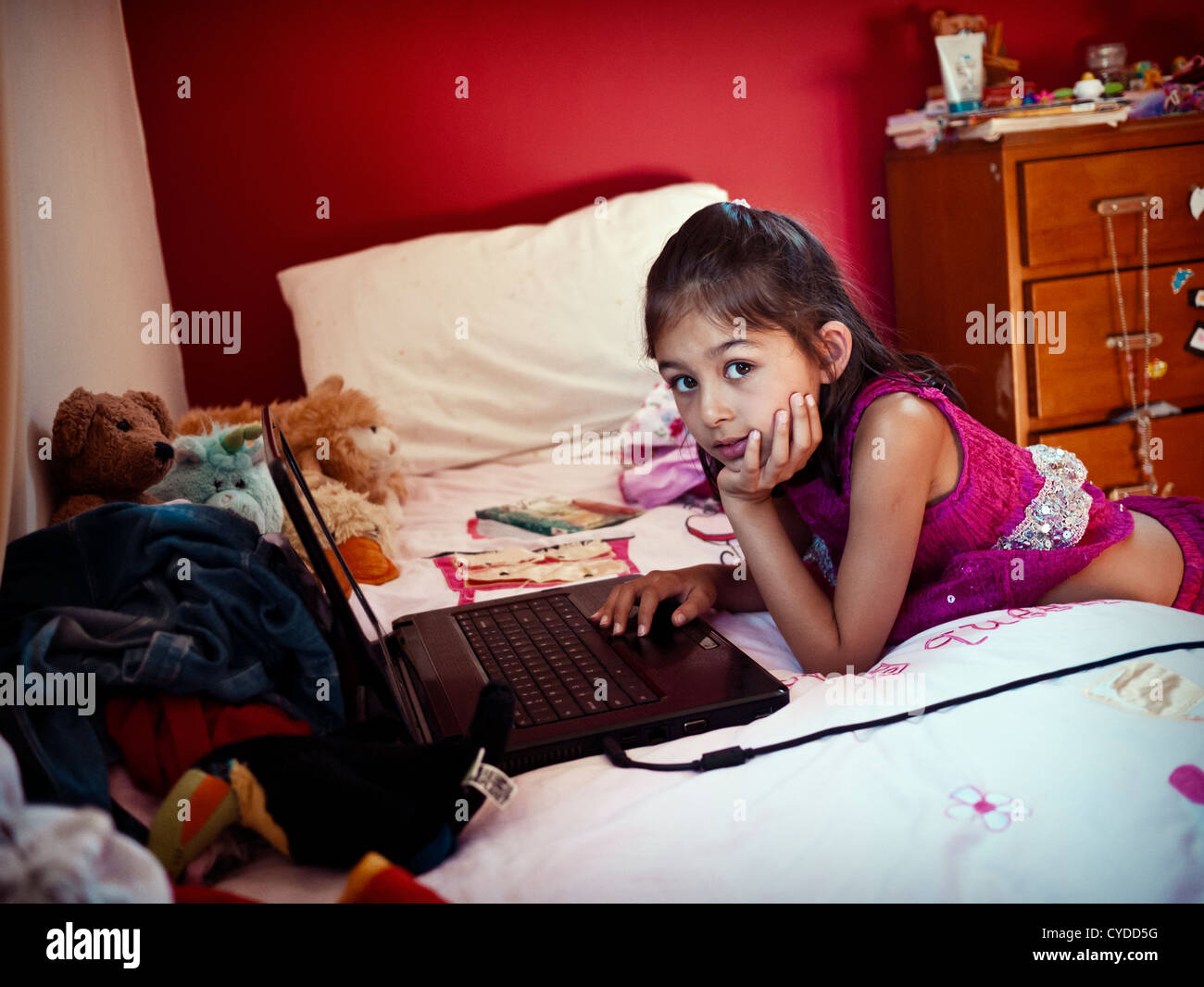 Chica con ordenador portátil en su cama. Foto de stock