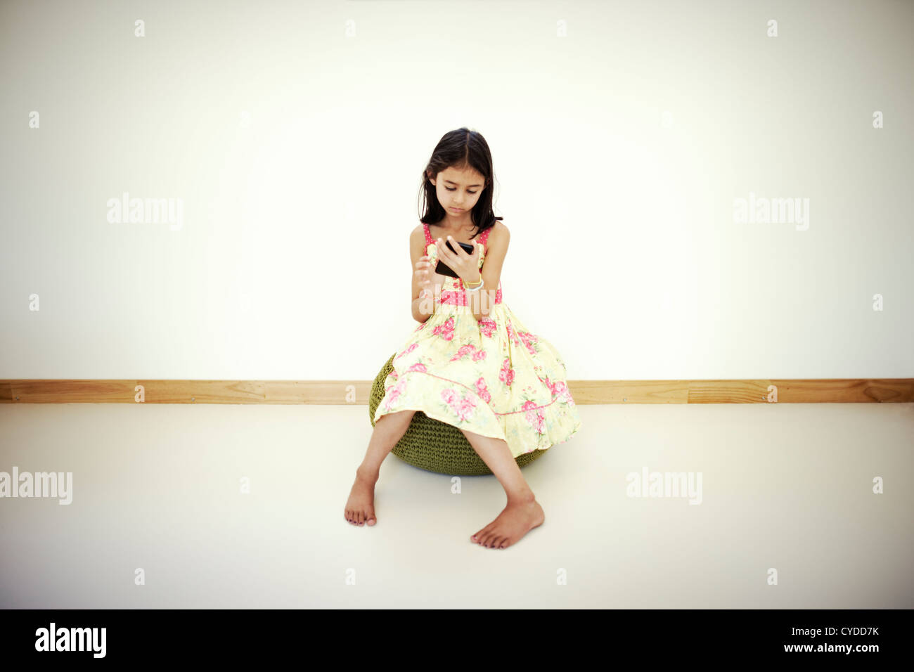 Niña usa smartphone en sala blanca Foto de stock