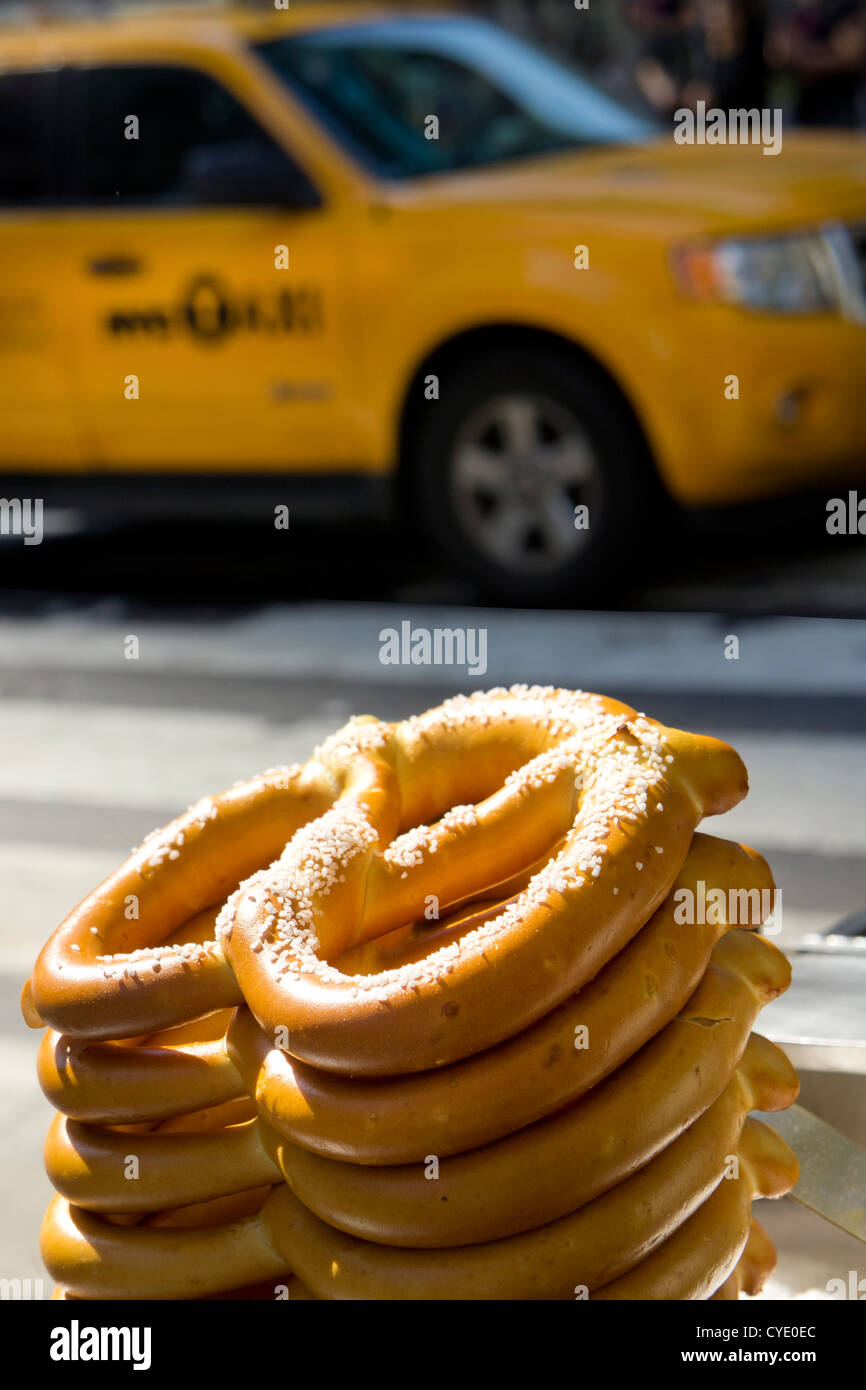 Bagels sobre vendedores ambulantes calado en vereda con taxi amarillo en el fondo, Nueva York, Nueva York, EE.UU. Foto de stock