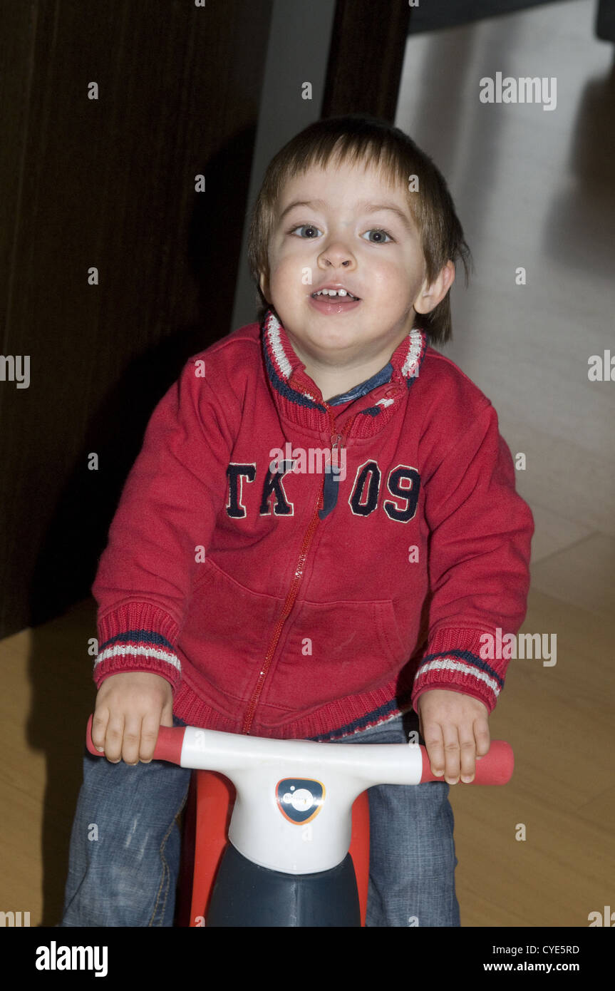 Niño de 2 años montando su moto de plástico Fotografía de stock