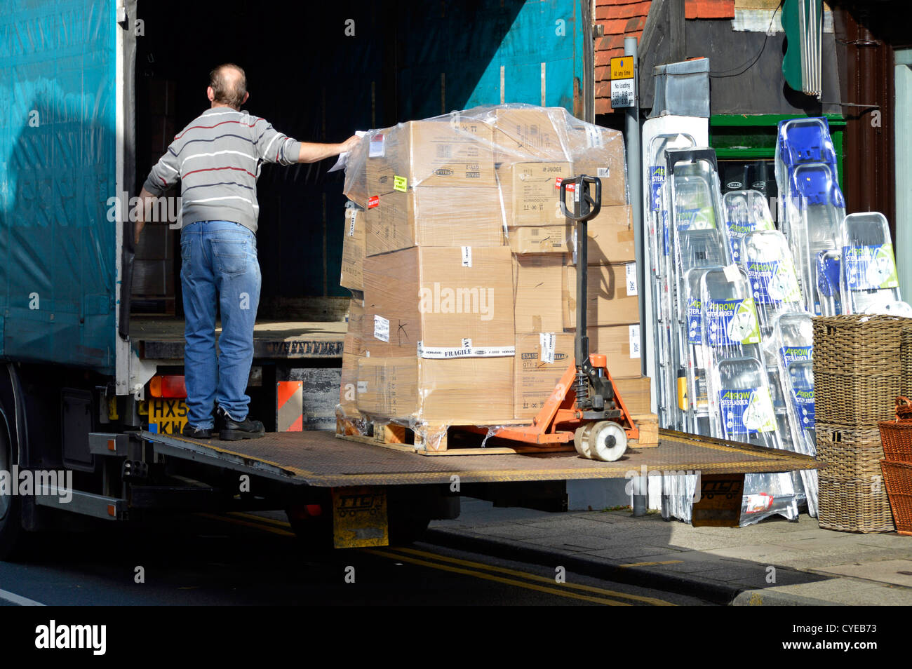 Cajas de mudanza fuera del camión, haciendo entrega de mercancías a un  proveedor fuera de una tienda de la calle alta bajando a la acera con  portón elevador Sevenoaks Kent UK Fotografía