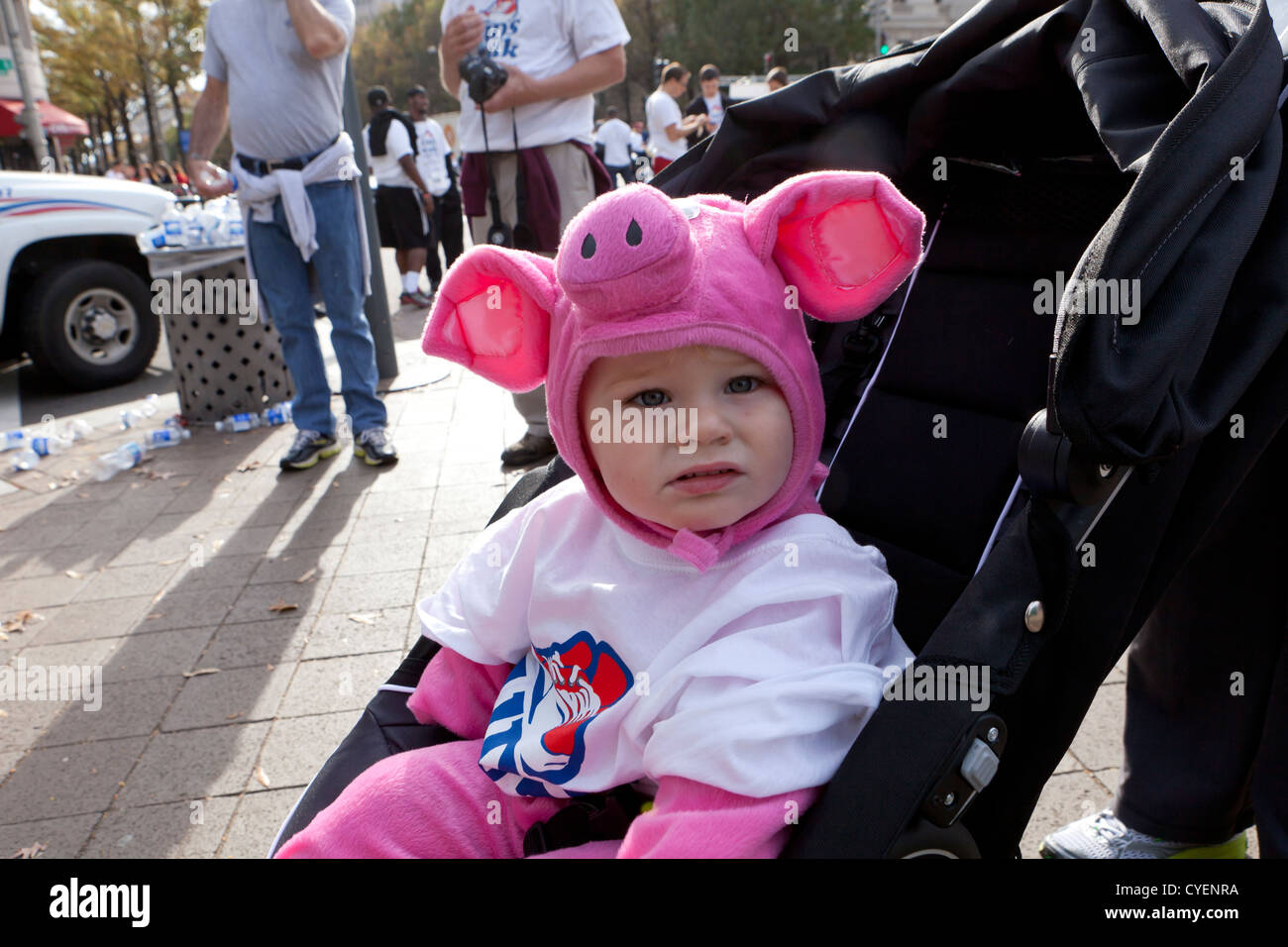 Bebé caucásica vestidas en trajes piggy sentado en el cochecito Foto de stock