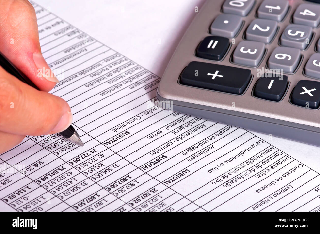 Empresario haciendo cuentas junto a una calculadora. Foto de stock