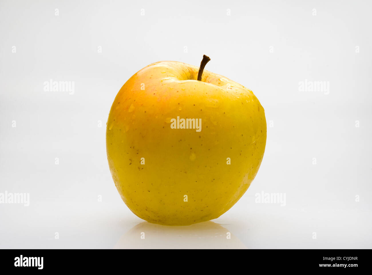 Manzana amarilla fresca con injerto waterdrops sobre fondo blanco. Foto de stock