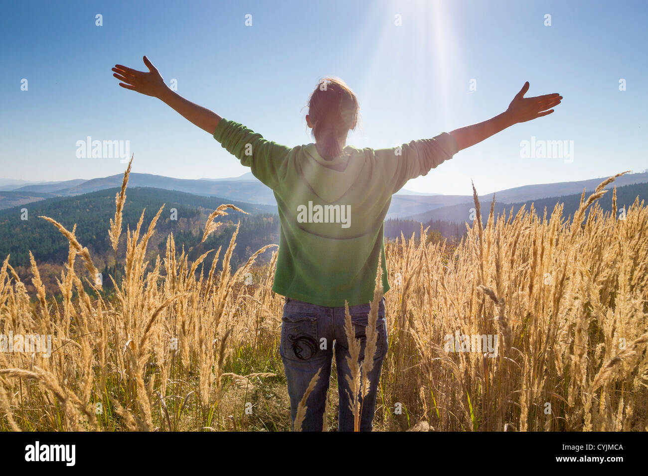 Niña feliz, disfrutando de la belleza del soleado día de otoño en lo alto de las montañas Foto de stock