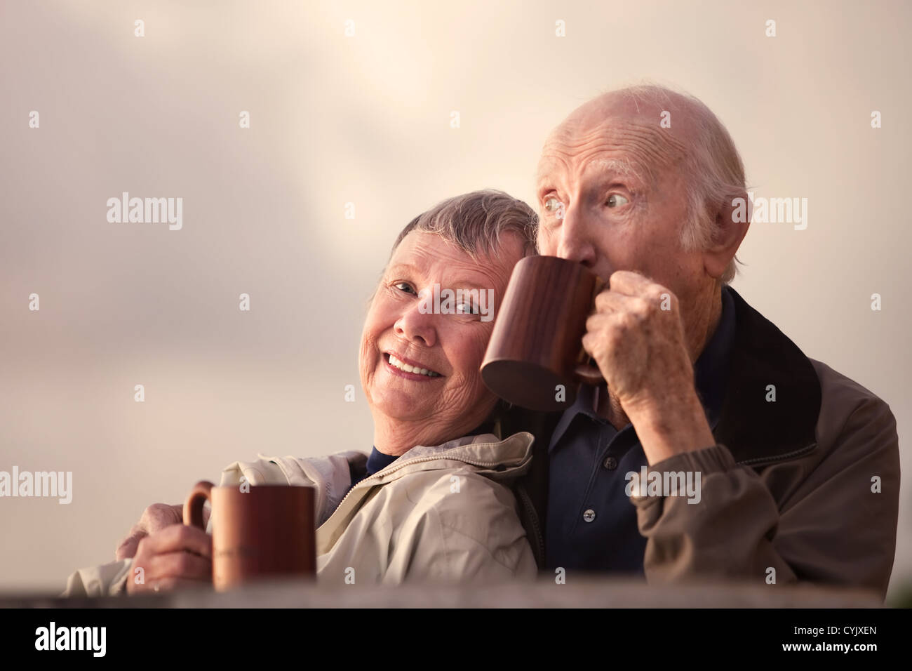 Adorable pareja senior afuera bebiendo tazas Foto de stock