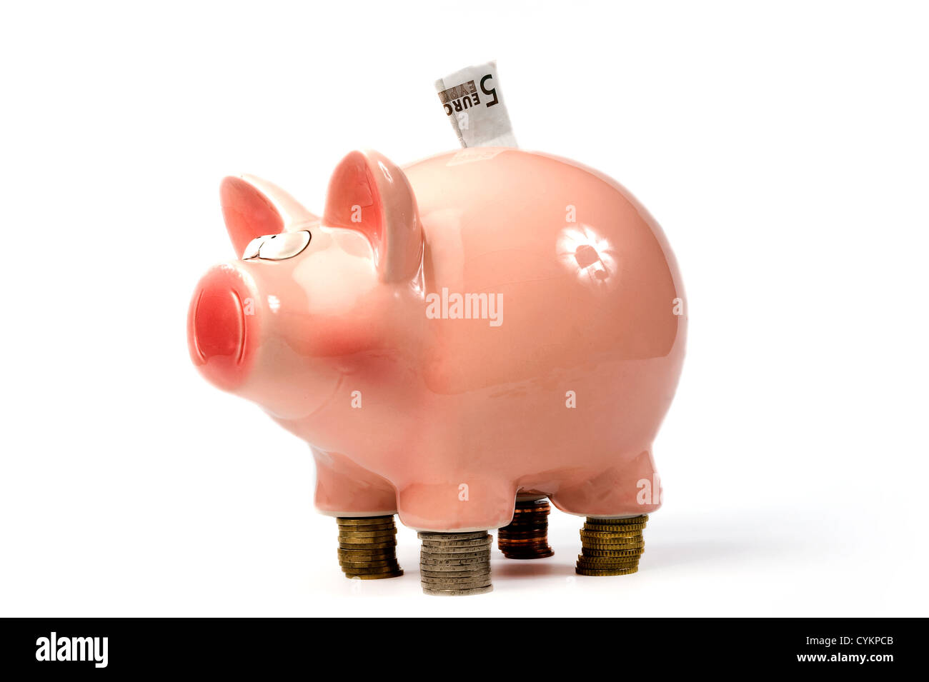 Un ahorro de cerdo de pie sobre las monedas de euro grapados Foto de stock