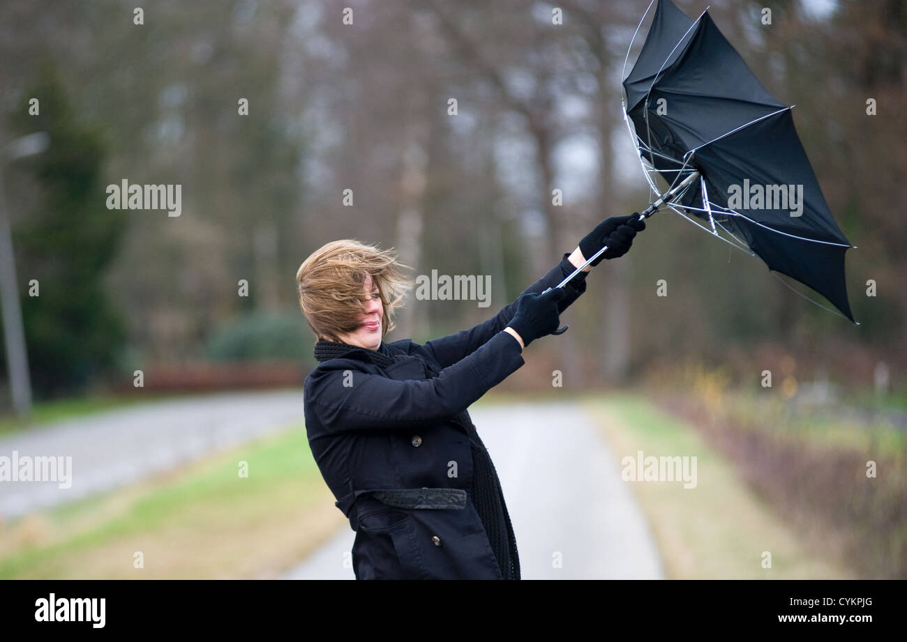 Una mujer joven está luchando contra la tormenta con su paraguas Foto de stock