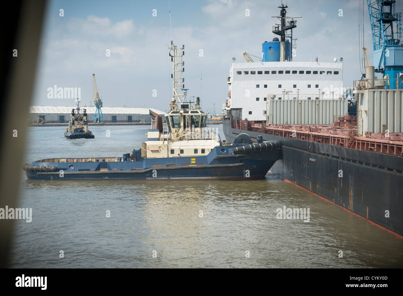 Remolcador empujando buque en puerto urbano Foto de stock
