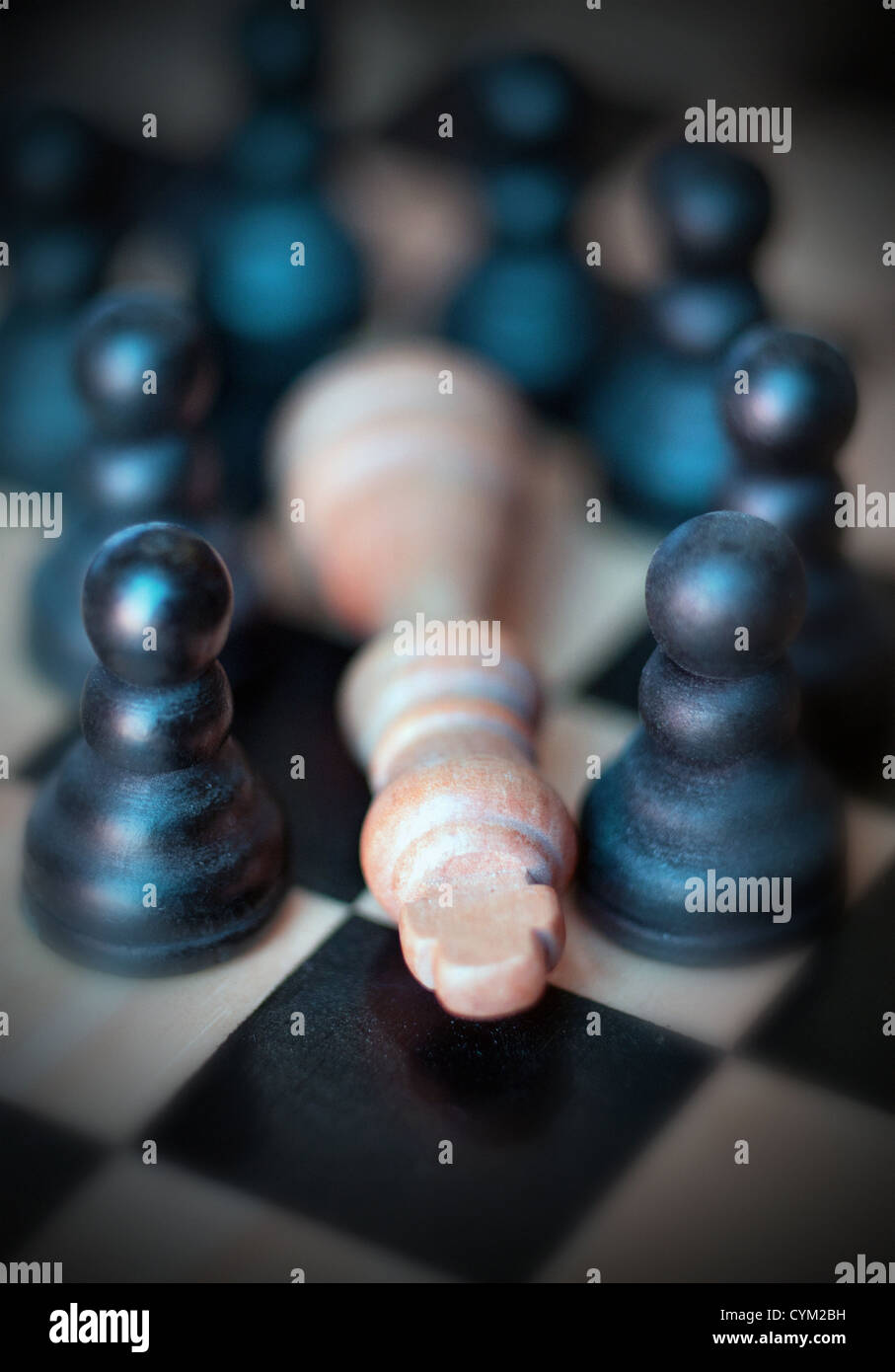 Los hombres de ajedrez los peones que rodean caído rey Foto de stock