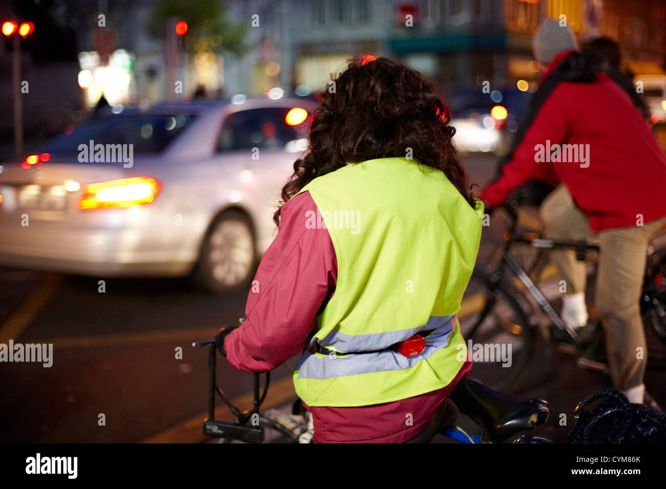 Mujer vistiendo un chaleco de alta visibilidad en bicicleta por la noche en el centro de la ciudad de Dublin república de Irlanda Foto de stock