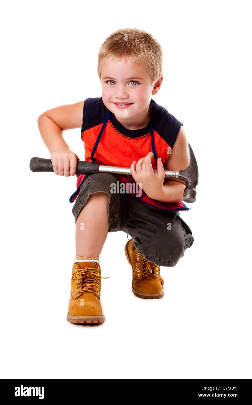 Lindo muchacho sosteniendo un martillo pesado en su regazo mientras en cuclillas, aislado. Foto de stock