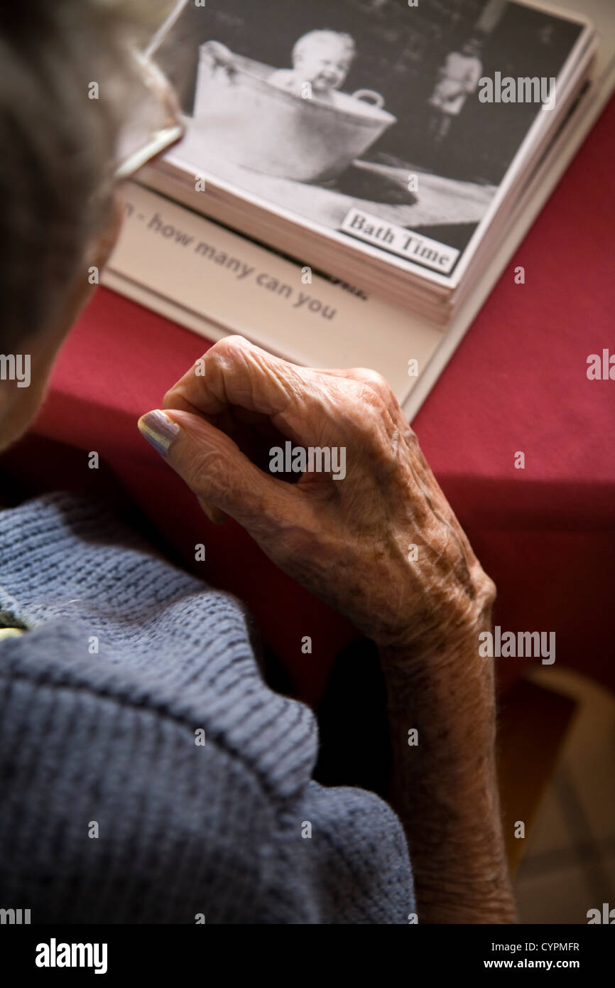 Senior / pensionista dama / persona sosteniendo / mirando un álbum / libro de fotografías antiguas: parte de la terapia en un hogar de ancianos. En el Reino Unido. Foto de stock