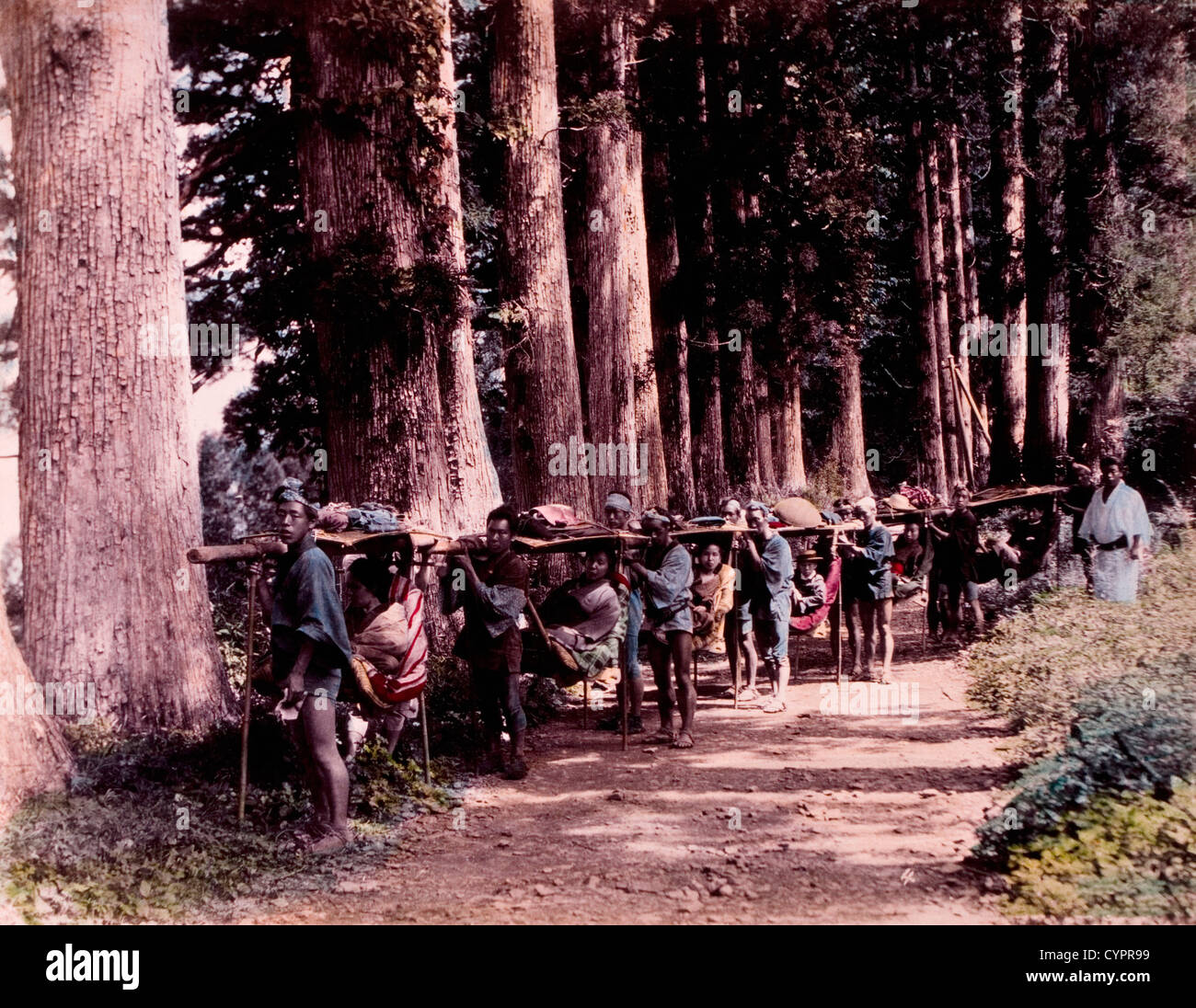 Los hombres japoneses llevando las mujeres japonesas en viajar sillas a lo largo de caminos rurales, Kusakabe Kimbei Hand-Colored, Fotografía, circa 1870 Foto de stock
