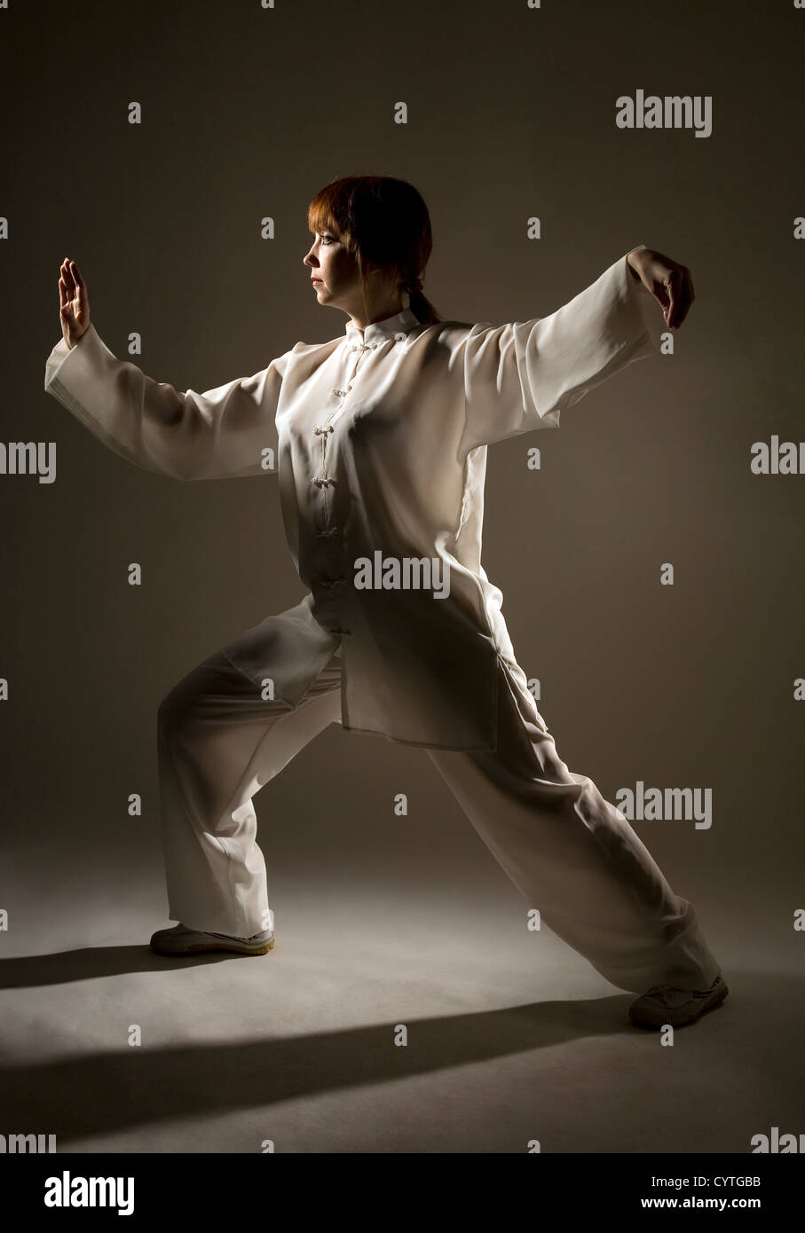 Joven en traje blanco que el taiji chuan ejercicio en studio Foto de stock
