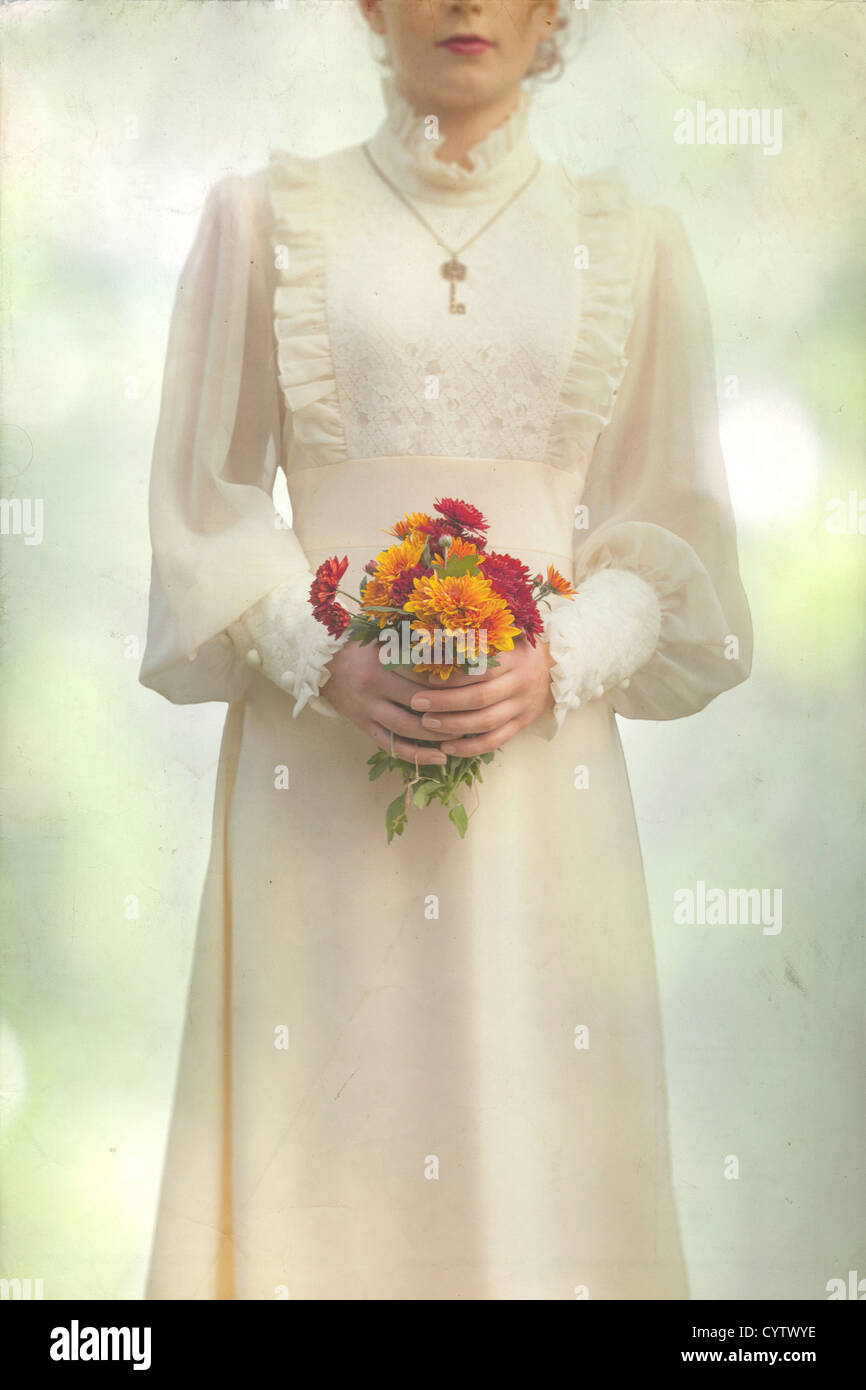 Una mujer en un vestido victoriano en un prado con un ramo de flores Foto de stock