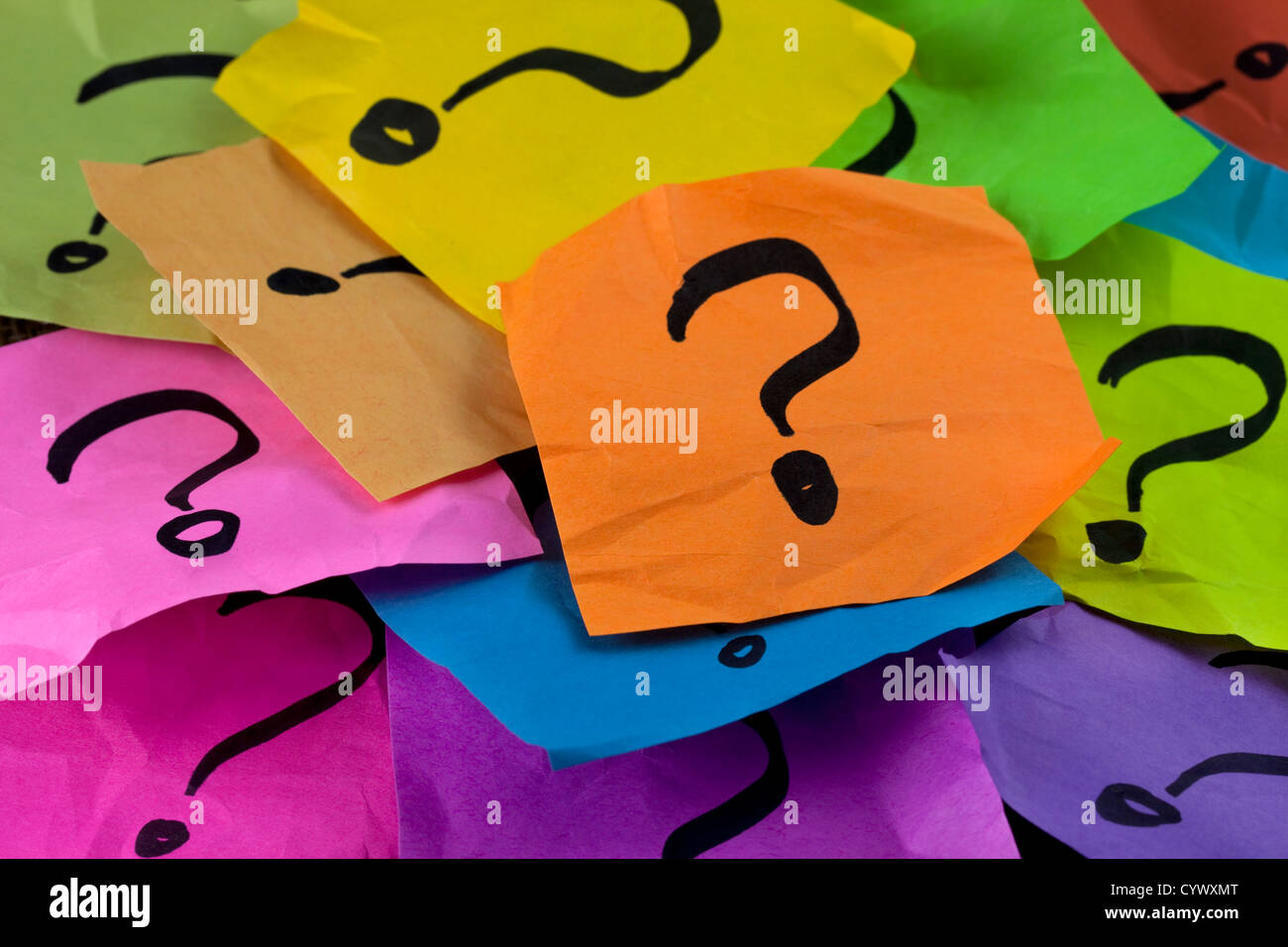 Preguntas, toma de decisiones o la incertidumbre concepto - un montón de coloridos arrugado notas adhesivas con signos de interrogación Foto de stock