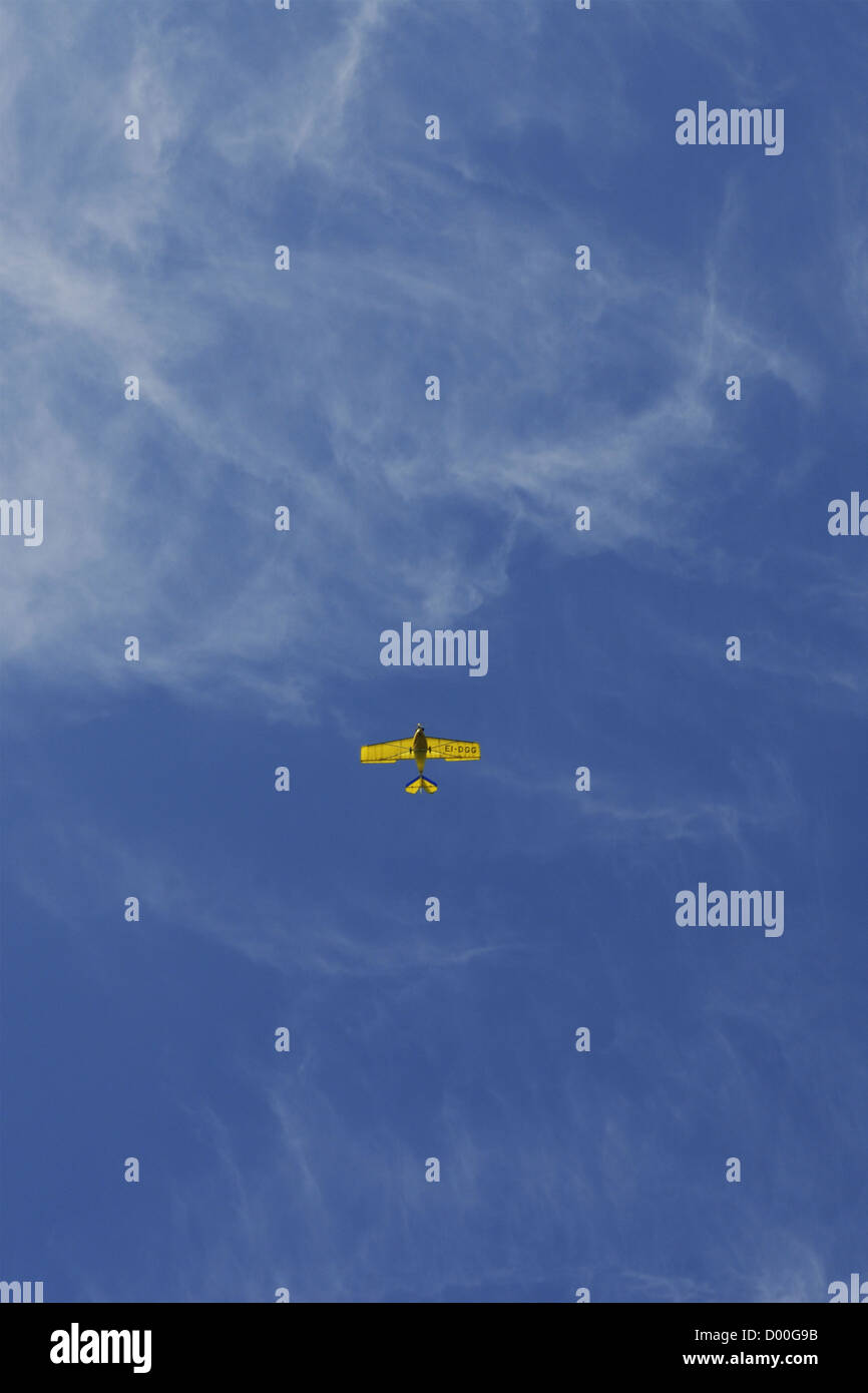 Amarillo pequeño avión contra un cielo azul veranos con nubes cirrus. Foto de stock