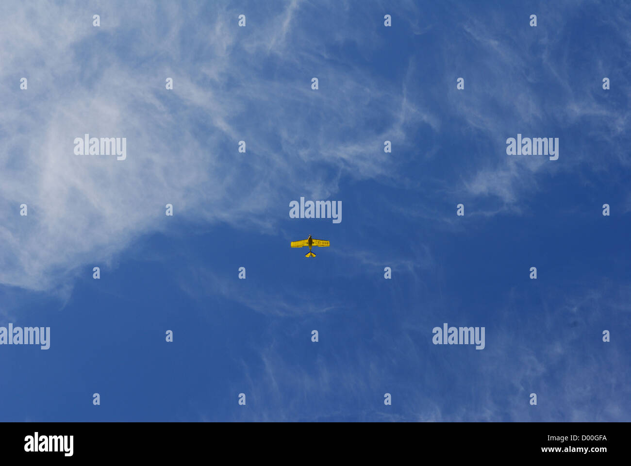 Amarillo pequeño avión contra un cielo azul veranos con nubes cirrus. Foto de stock