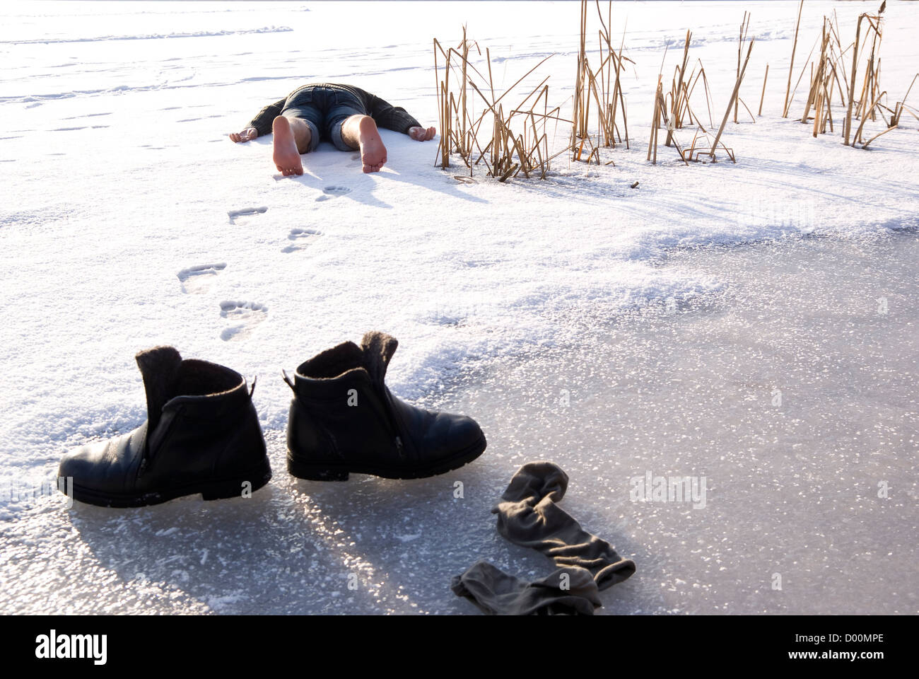 Hombre cansado descalzo a acostarse sobre la nieve Foto de stock