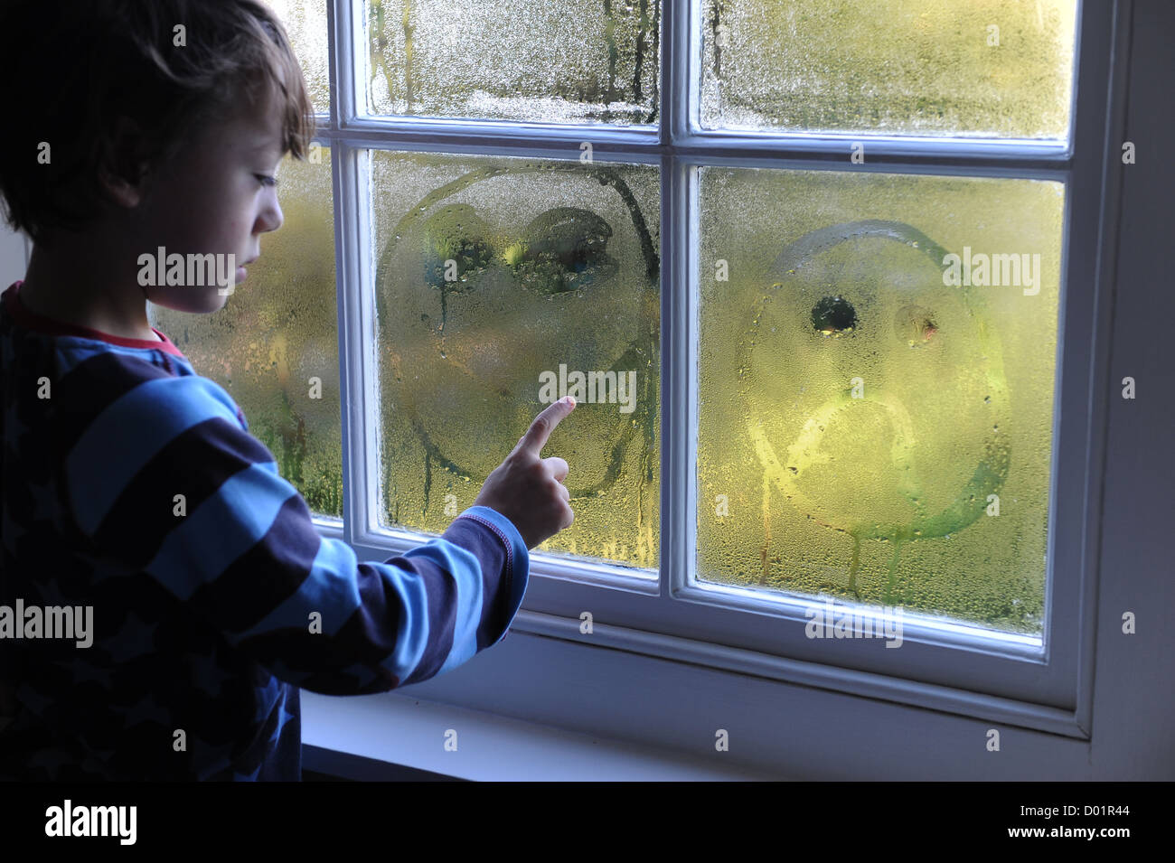 Niño de 8 años el dibujo de una cara triste en una ventana de la  condensación Fotografía de stock - Alamy