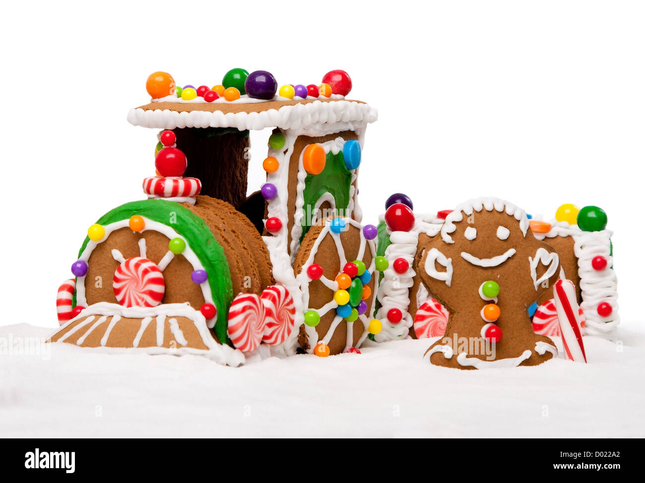 Gingerbread Polar Express Train y hombre feliz navidad cubierto con nieve y coloridos dulces sobre un paisaje de invierno, aislado Foto de stock