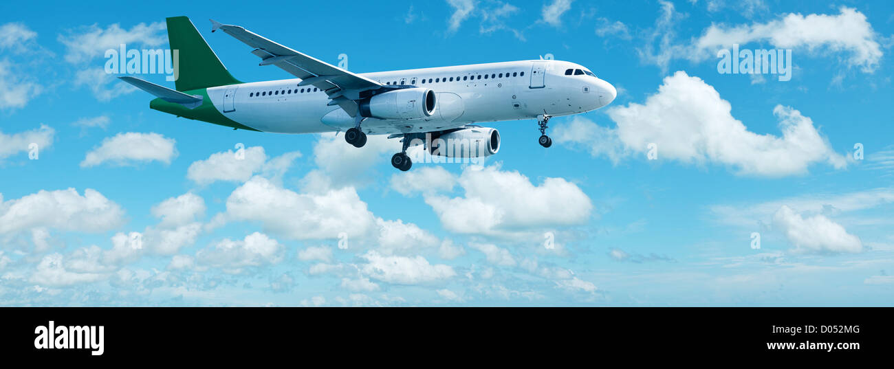 Avión en un azul cielo nublado está maniobrando para aterrizar. Composición panorámica. Foto de stock