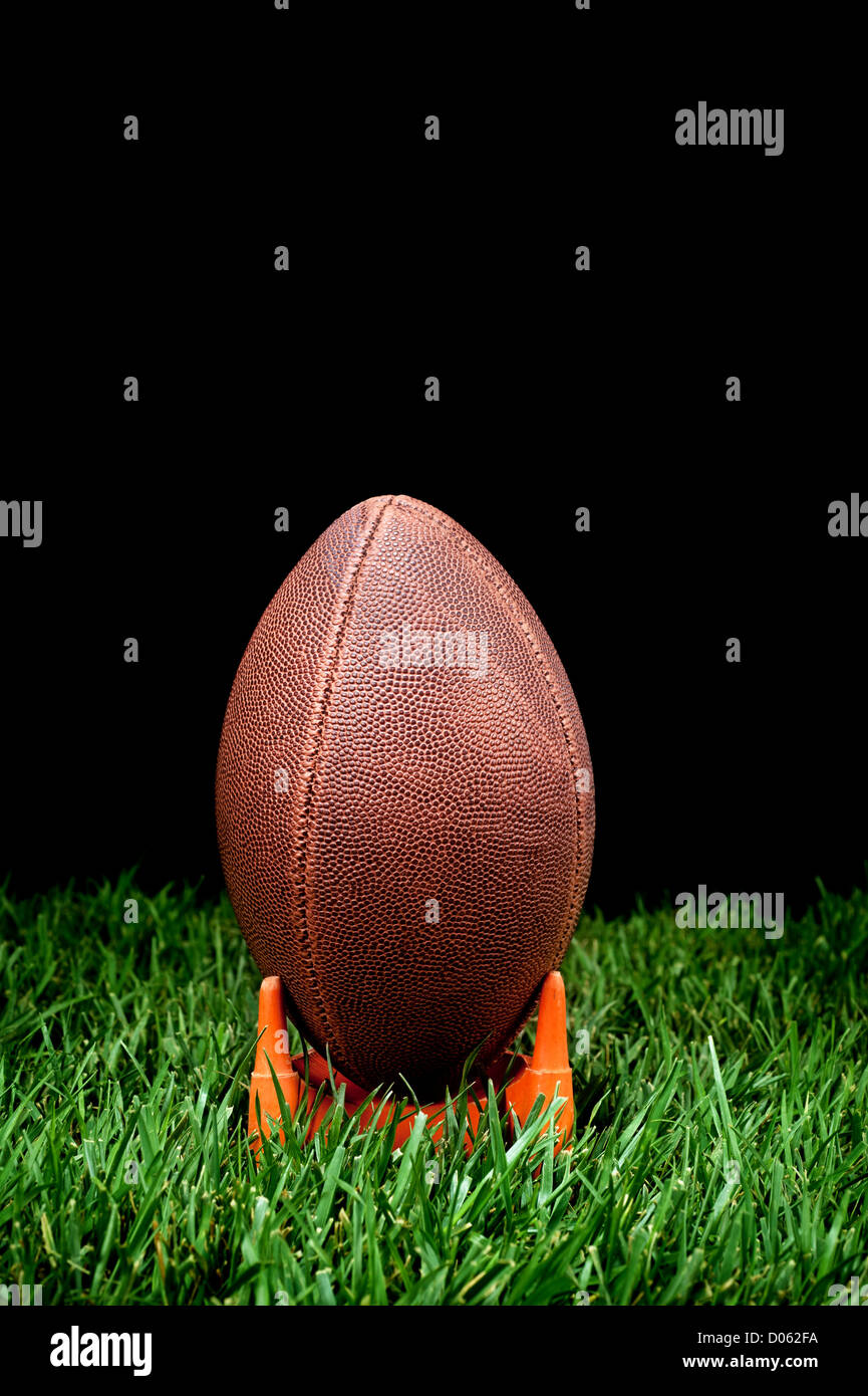 Un kickoff de fútbol en un campo de hierba con un fondo negro para representar la noche. Foto de stock