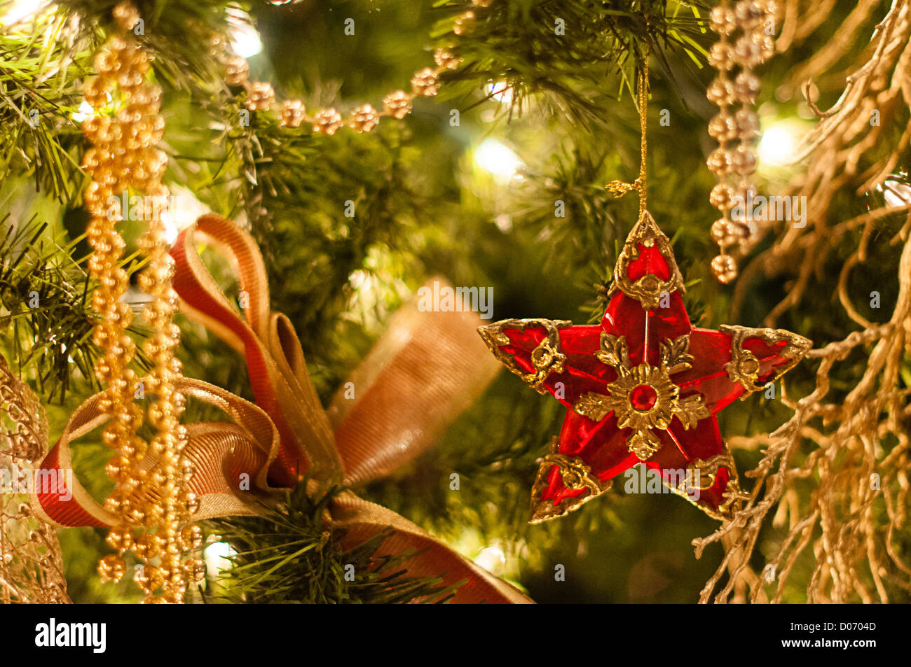 Cerca de una estrella roja y adornos de oro en un tradicional árbol de Navidad Foto de stock