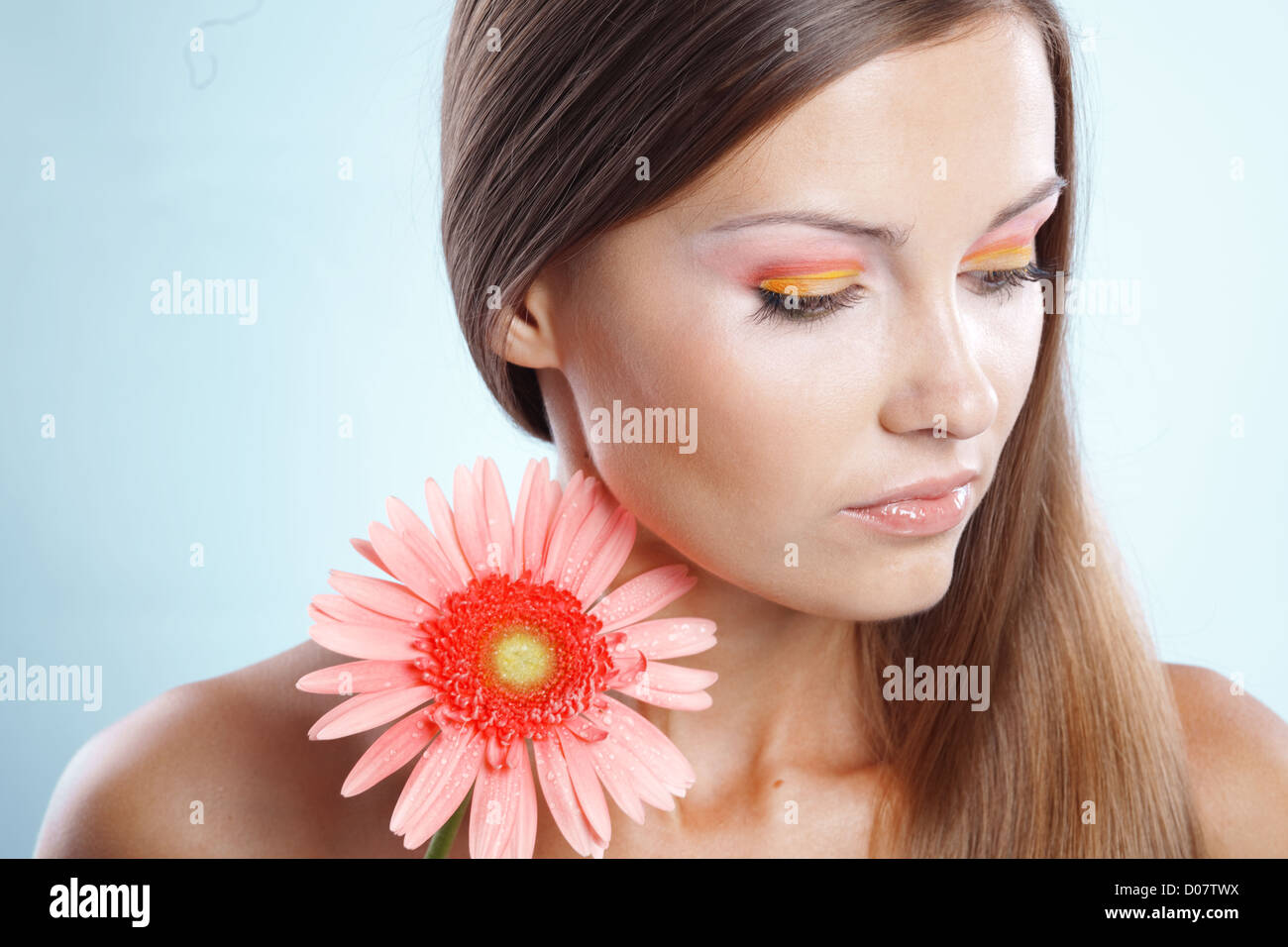 Hermosa mujer con maquillaje fresco y claro manteniendo la piel rosa daisy  sobre blue studio shot Fotografía de stock - Alamy