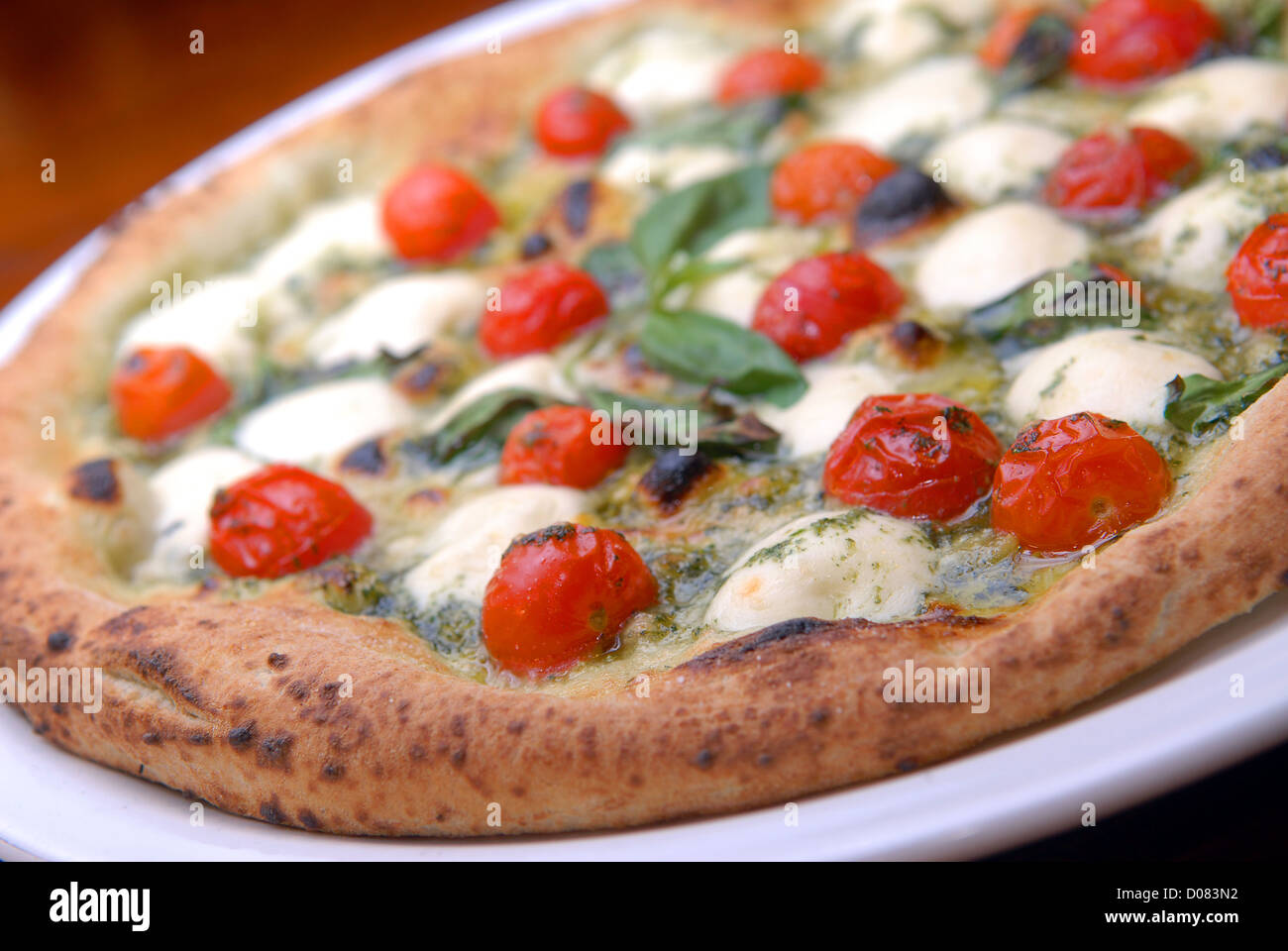 Pizza con tomates y queso mozzarella sobre una tabla Foto de stock