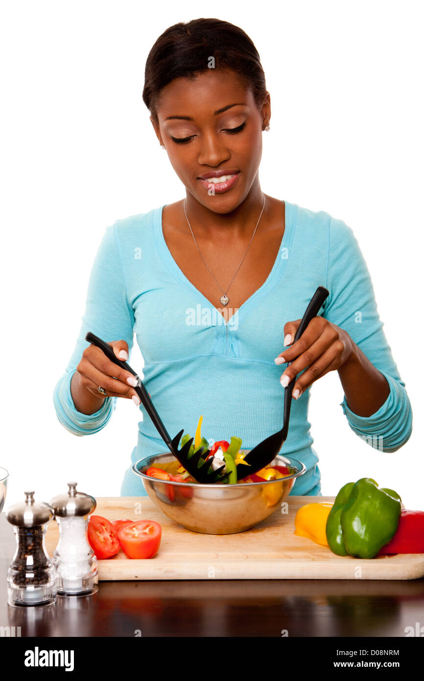 Conscientes de la salud hermosa joven arrojando saludables ensaladas orgánicas en cocina, aislado. Foto de stock