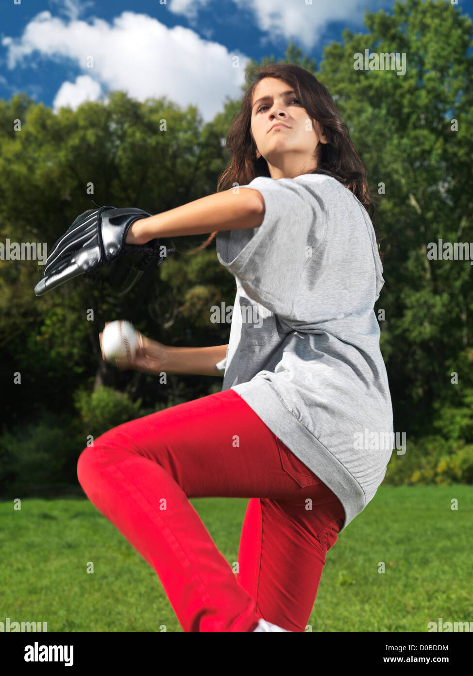 Captura la acción de una adolescente con un guante de béisbol, throing practicando una bola, verano activo estilo de vida. Foto de stock