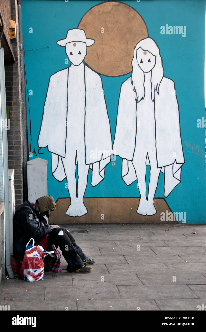 Hombre sin hogar en la calle con una bolsa de plástico en Union Jack de mural de moda tienda de ropa de segunda mano. Foto de stock