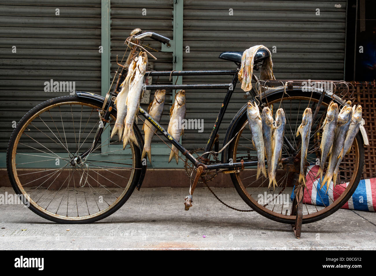 Vieja bicicleta con peces colgando, Macao, China Foto de stock