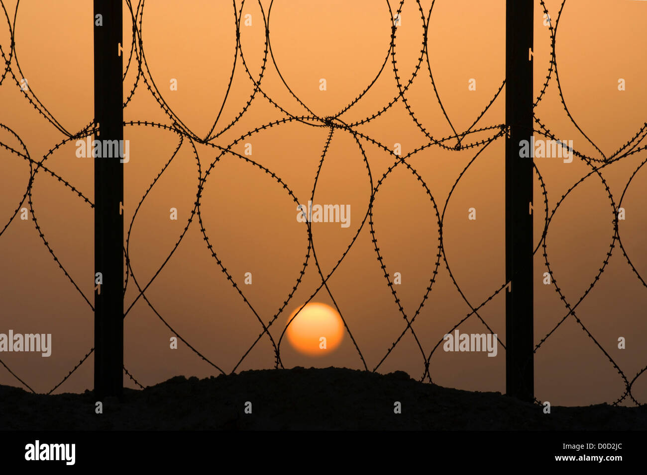 Vista de la puesta de sol desde detrás del alambre de serpentina en la base aérea de Al Taqaddum en Irak la provincia de Al Anbar Foto de stock