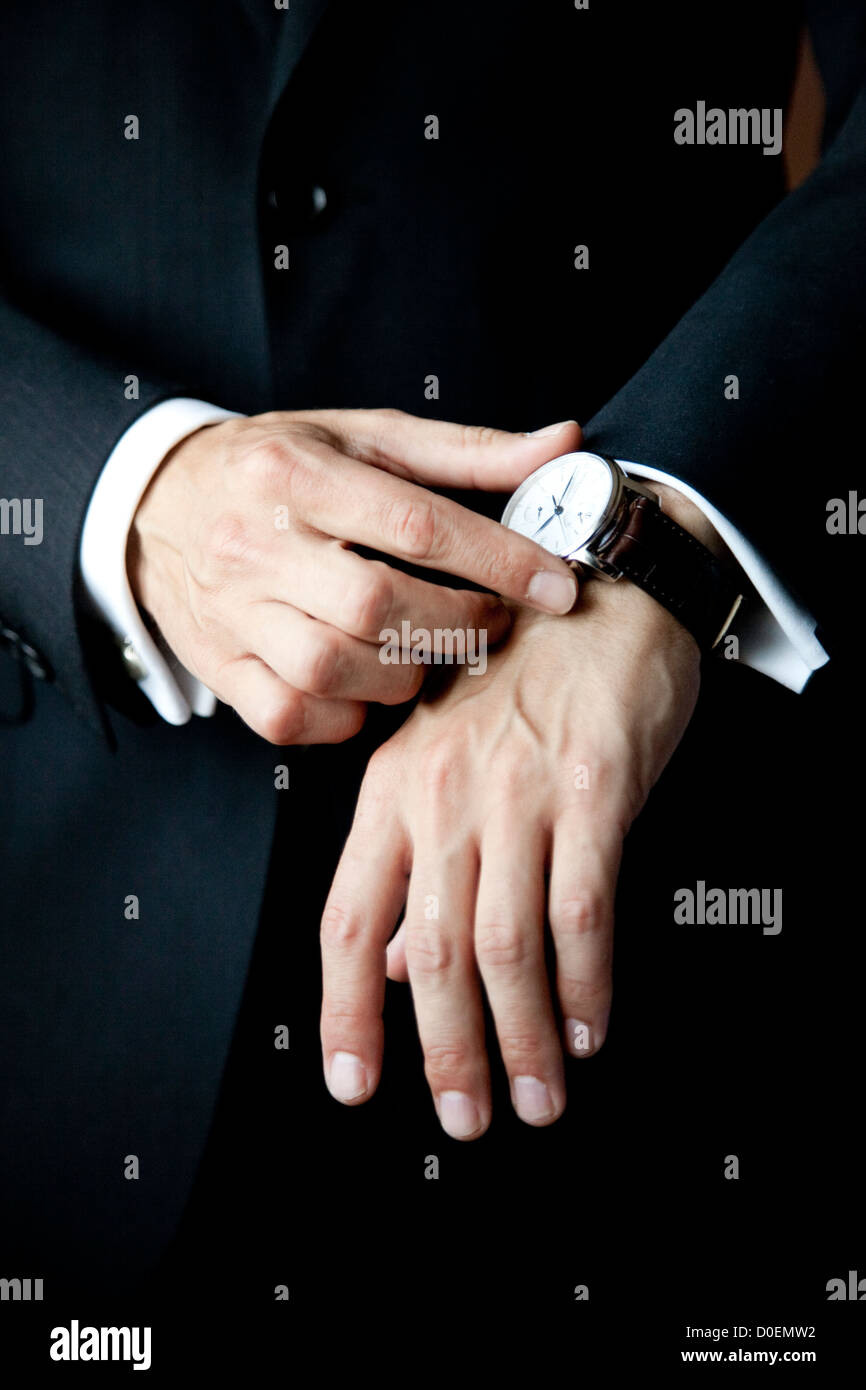 Manos de un hombre tocando su reloj Foto de stock