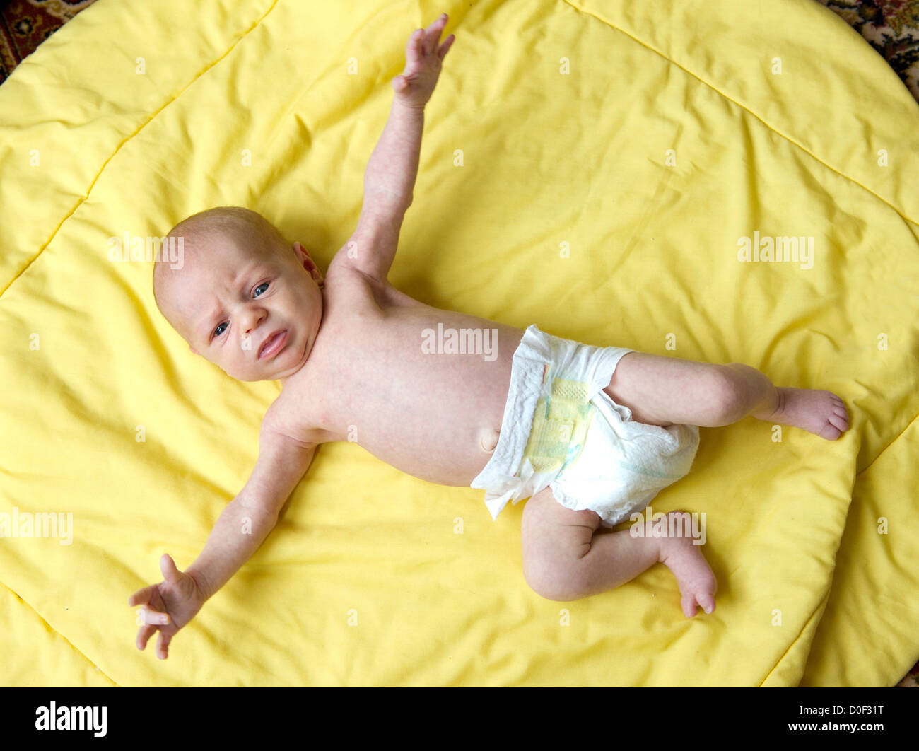 Un bebé recién nacido de un mes de antigüedad mostrando el 'Moro' Reflex, un sorprendido con apariencia de manos tendidas Foto de stock