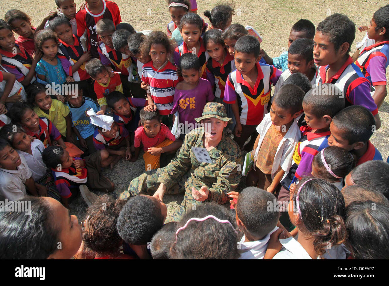 Un ayudante médico del Hospital de la Marina estadounidense muestra a los niños una tarjeta trick durante una misión humanitaria, 12 de octubre de 2012 en una remota aldea en Timor Oriental. Foto de stock
