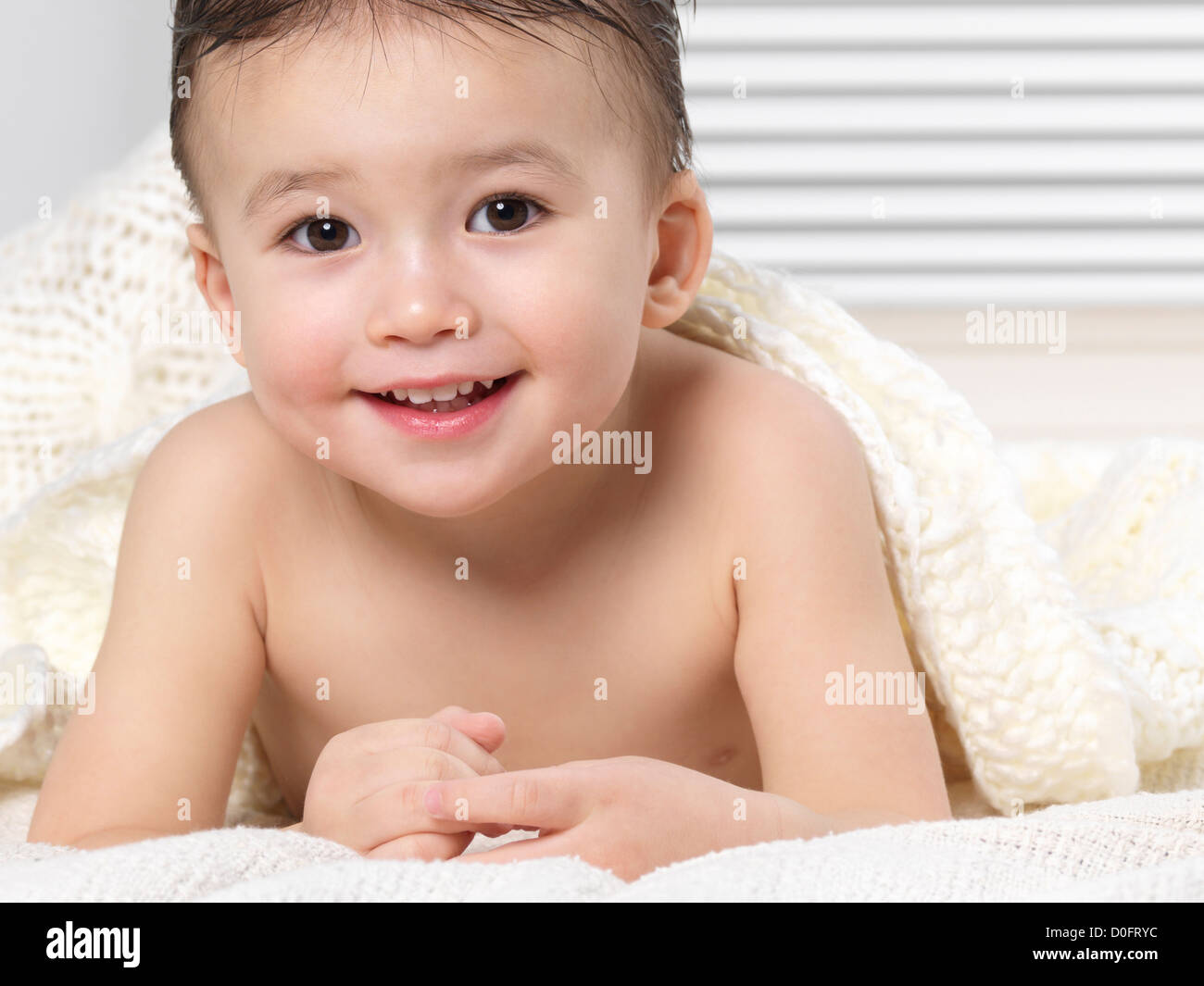 Retrato De Un Lindo Bebe De Dos Anos Sonriente Nino Acostado En Una Cama Con Una Cobija Fotografia De Stock Alamy